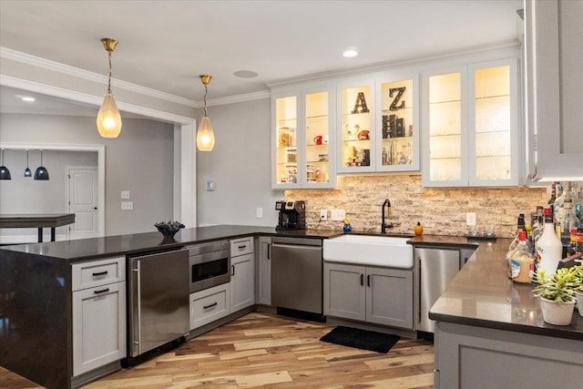 kitchen featuring appliances with stainless steel finishes, ornamental molding, a peninsula, hanging light fixtures, and a sink