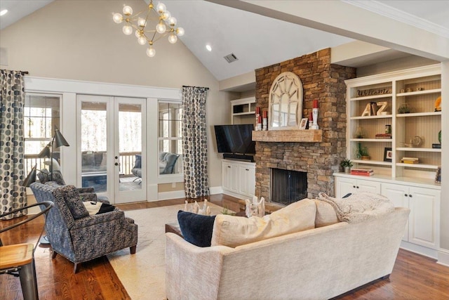 living area featuring visible vents, wood finished floors, a stone fireplace, french doors, and built in shelves