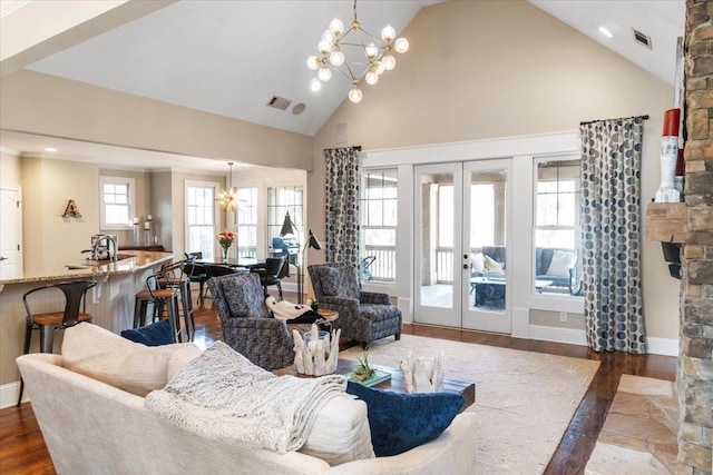 living area with a chandelier, high vaulted ceiling, wood finished floors, baseboards, and french doors