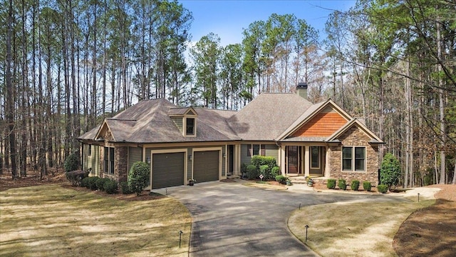 craftsman-style home featuring a garage, stone siding, driveway, and a front lawn