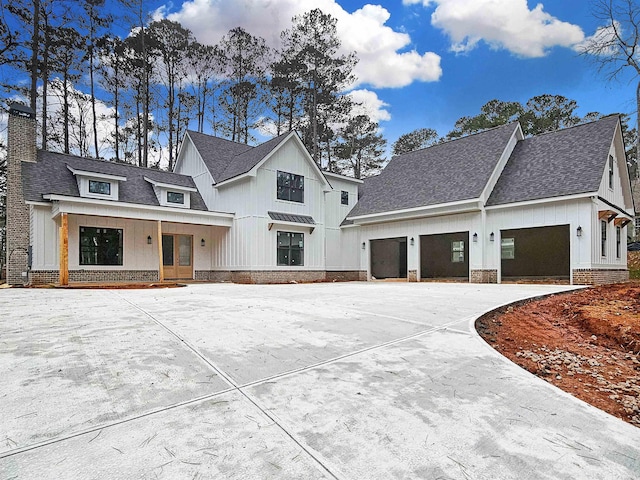 modern inspired farmhouse featuring brick siding, a chimney, and roof with shingles