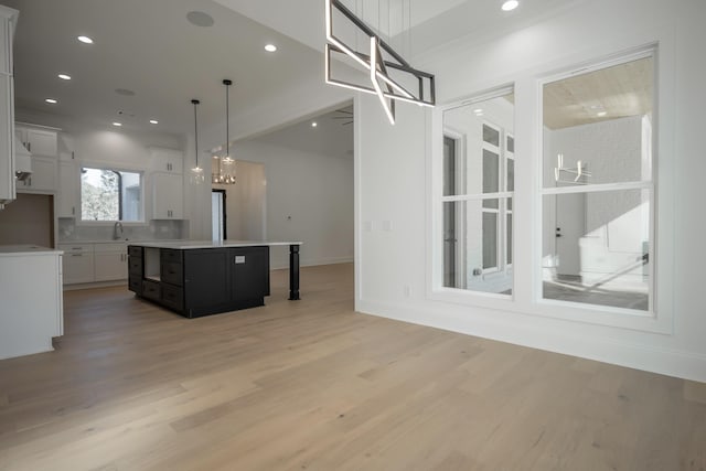 kitchen with a center island, light countertops, light wood-style floors, white cabinetry, and a sink