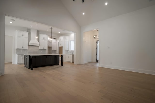 kitchen with high vaulted ceiling, premium range hood, white cabinets, open floor plan, and light wood-type flooring