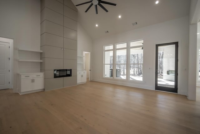 unfurnished living room with light wood finished floors, recessed lighting, visible vents, ceiling fan, and high vaulted ceiling