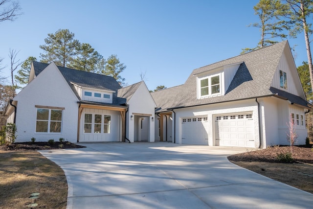 modern farmhouse style home featuring concrete driveway, roof with shingles, an attached garage, board and batten siding, and brick siding