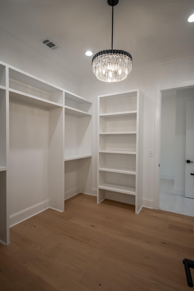 spacious closet featuring visible vents, a chandelier, and wood finished floors