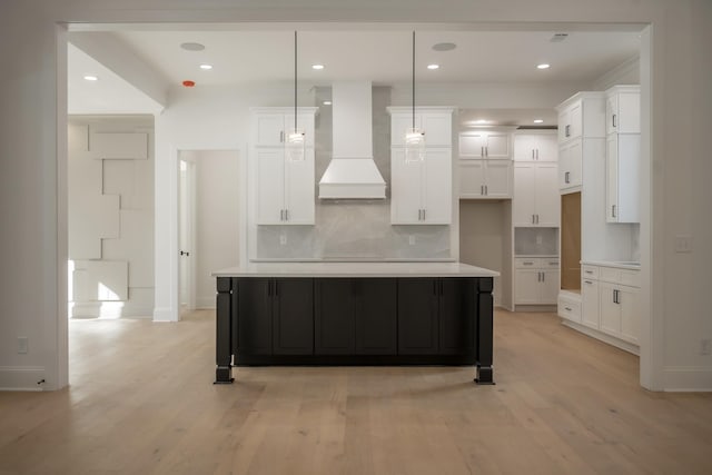 kitchen featuring light wood-type flooring, tasteful backsplash, custom range hood, and white cabinets