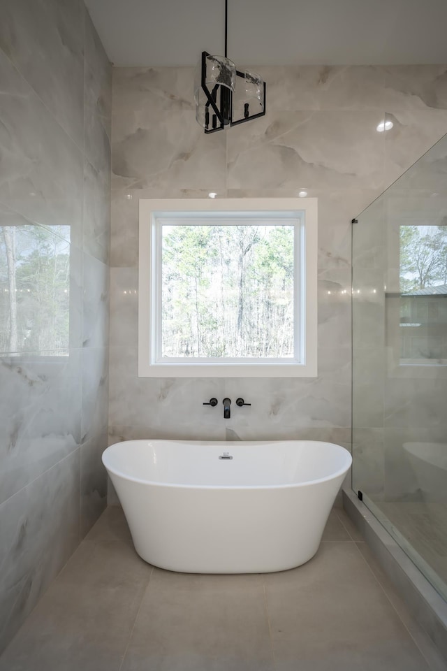 bathroom featuring tile patterned flooring, a freestanding bath, tile walls, and a walk in shower