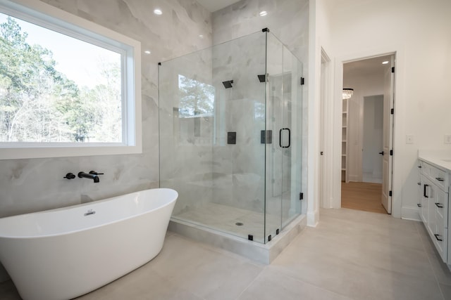 bathroom featuring a stall shower, tile patterned floors, a soaking tub, and vanity