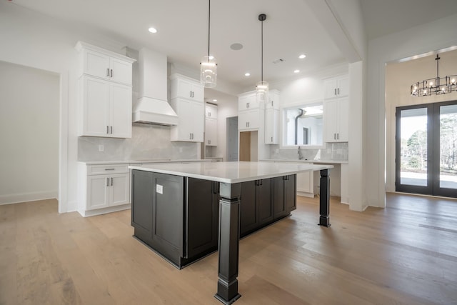 kitchen featuring french doors, light wood-style flooring, white cabinetry, and custom range hood