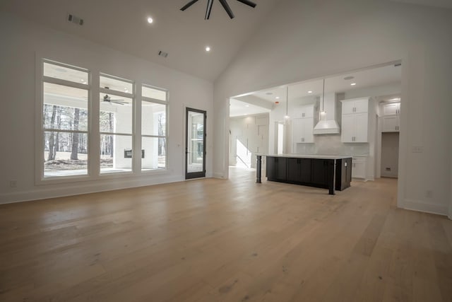 unfurnished living room with light wood-style floors, ceiling fan, visible vents, and high vaulted ceiling