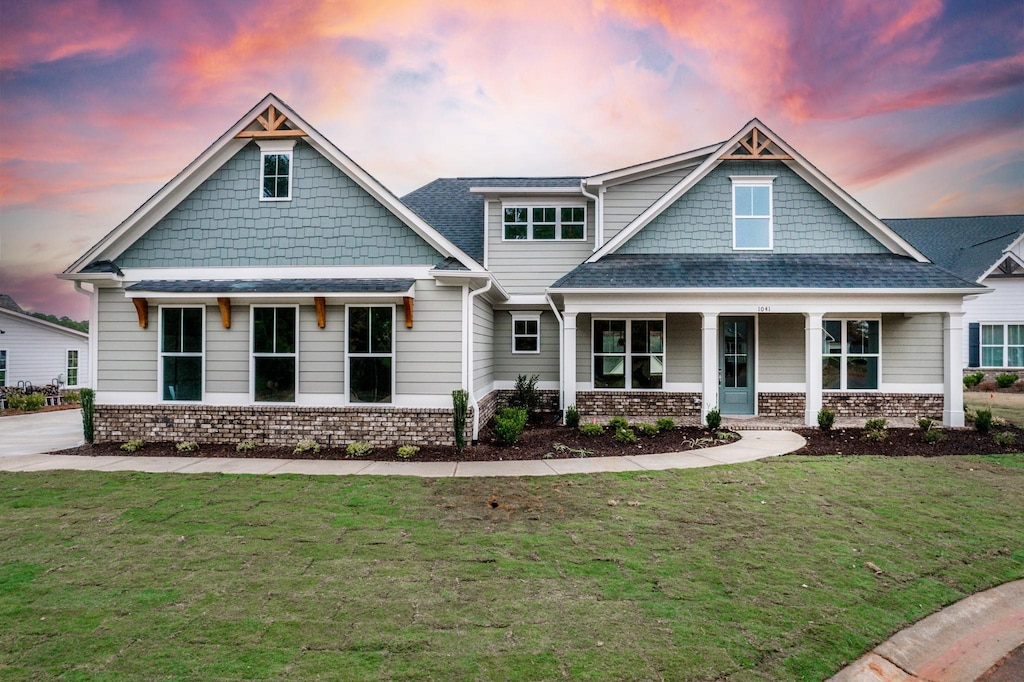 craftsman-style home with covered porch and a lawn