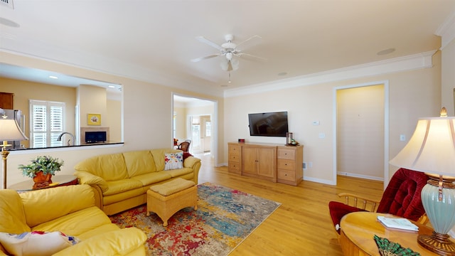 living room featuring crown molding, ceiling fan, sink, and light wood-type flooring