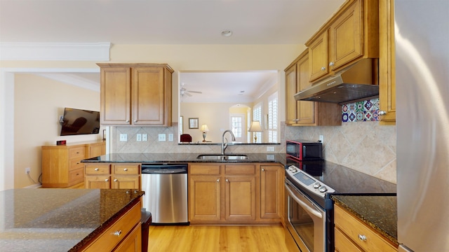 kitchen featuring appliances with stainless steel finishes, sink, light hardwood / wood-style flooring, and dark stone counters