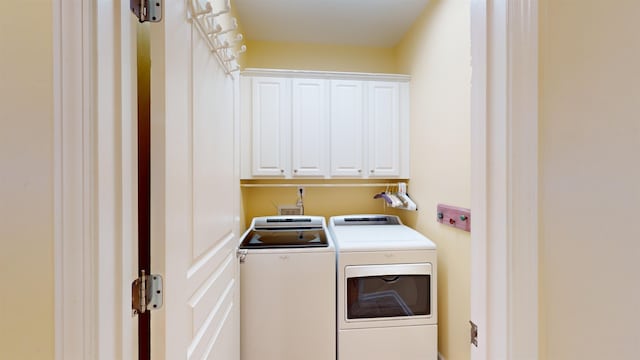 clothes washing area featuring cabinets and washing machine and dryer