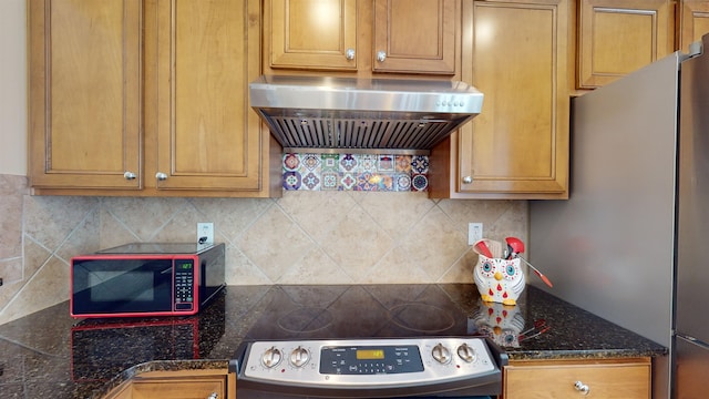 kitchen featuring dark stone counters, stainless steel stove, exhaust hood, and decorative backsplash