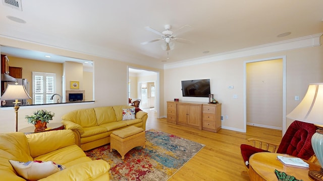 living room featuring ceiling fan, ornamental molding, sink, and light hardwood / wood-style floors