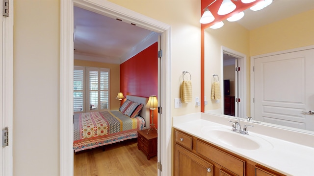 bathroom with crown molding, wood-type flooring, and vanity