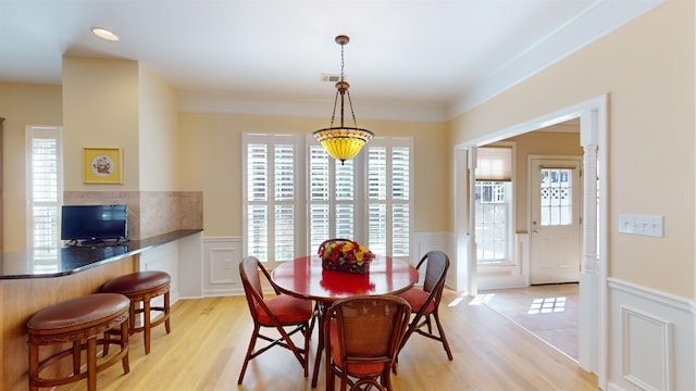 dining area with crown molding, a healthy amount of sunlight, and light hardwood / wood-style floors