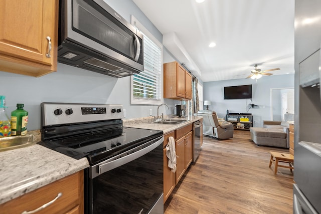 138B Little River Run, Eatonton, GA 31024 - kitchen featuring appliances with stainless steel finishes, ceiling fan, light wood-style floors, open floor plan, and brown cabinets