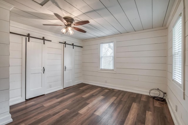 unfurnished bedroom with a barn door, dark wood finished floors, wood ceiling, and a ceiling fan