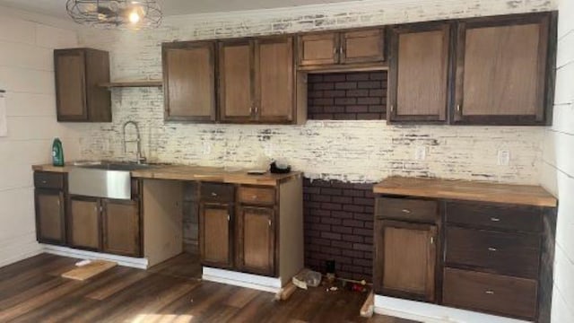 bar with dark wood-style floors, crown molding, and a sink