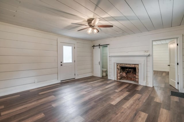 unfurnished living room featuring ceiling fan, a barn door, a fireplace, wood finished floors, and wood ceiling