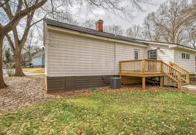 back of house featuring a yard, a chimney, a wooden deck, and central air condition unit