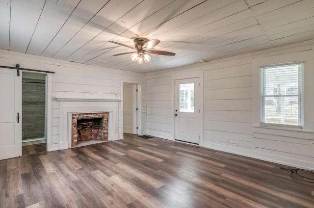 unfurnished living room featuring wood ceiling, a barn door, a fireplace, and wood finished floors