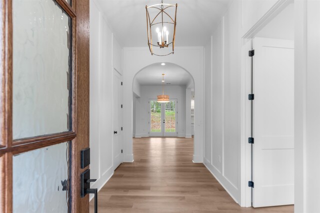 1731 Osprey Poynte, Greensboro, GA 30642 - hallway featuring french doors, a chandelier, light wood-type flooring, baseboards, and arched walkways