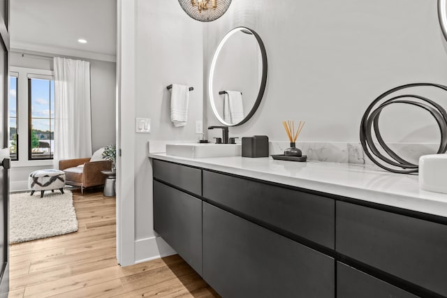 bathroom with baseboards, ornamental molding, wood finished floors, vanity, and recessed lighting