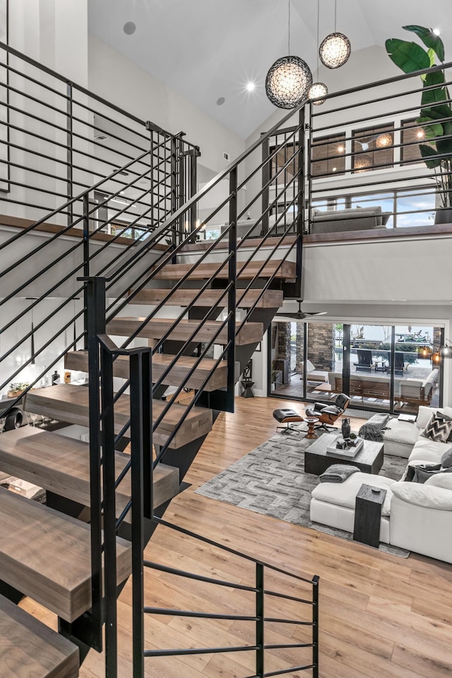 staircase with wood finished floors, a towering ceiling, and an inviting chandelier