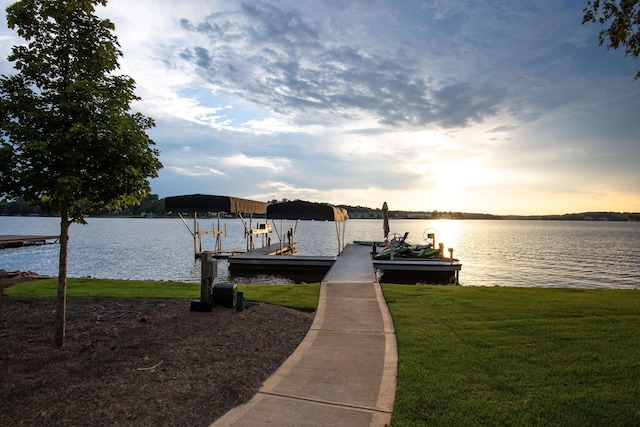 view of dock with a water view, a lawn, and boat lift