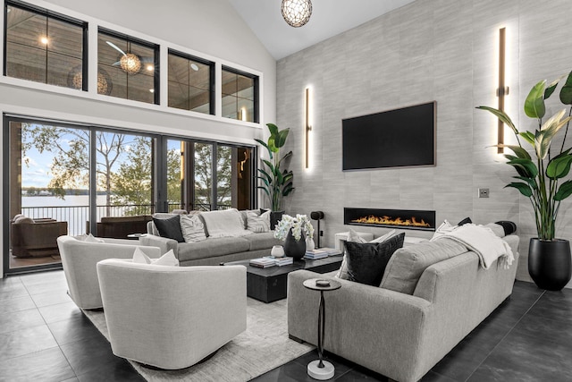 living room with dark tile patterned floors, a fireplace, and high vaulted ceiling