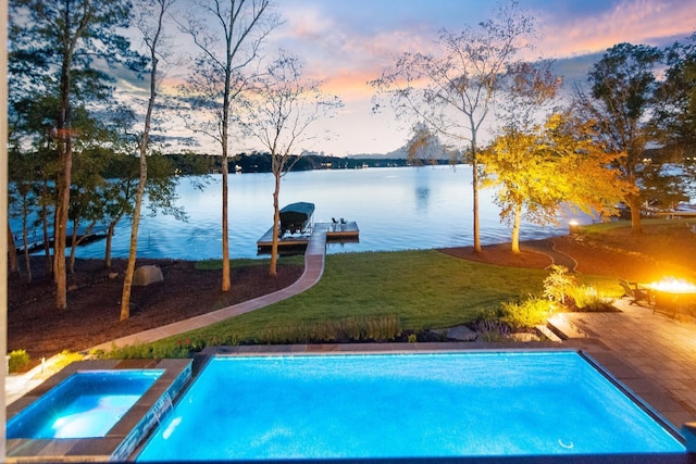 pool at dusk featuring an outdoor pool, an in ground hot tub, a water view, a dock, and a yard