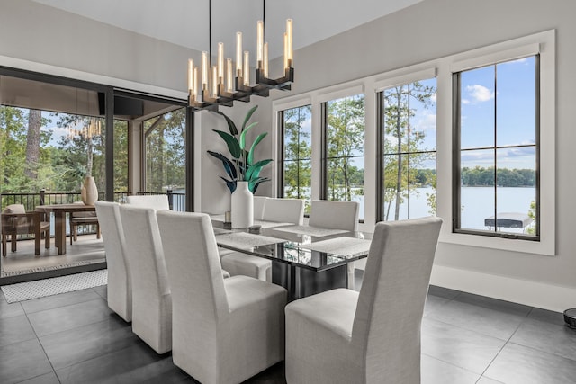 dining area with a chandelier, a water view, dark tile patterned floors, and baseboards