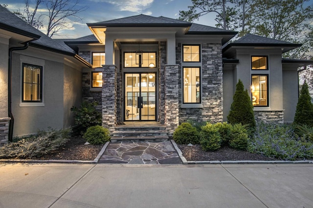 property entrance featuring stone siding, a shingled roof, and stucco siding