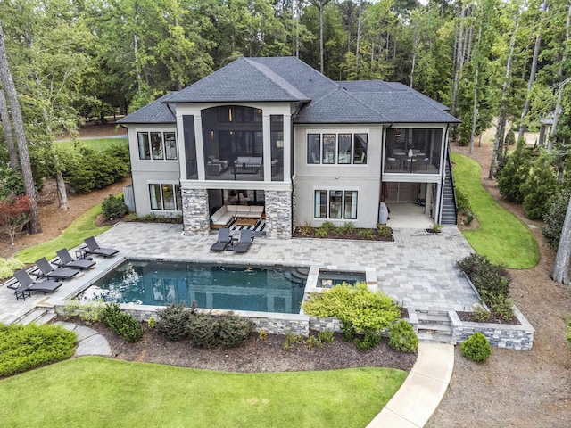 rear view of property with a sunroom, a patio area, stairs, and stone siding