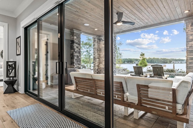 entryway with a water view, ornamental molding, a wall of windows, light wood-type flooring, and wooden ceiling