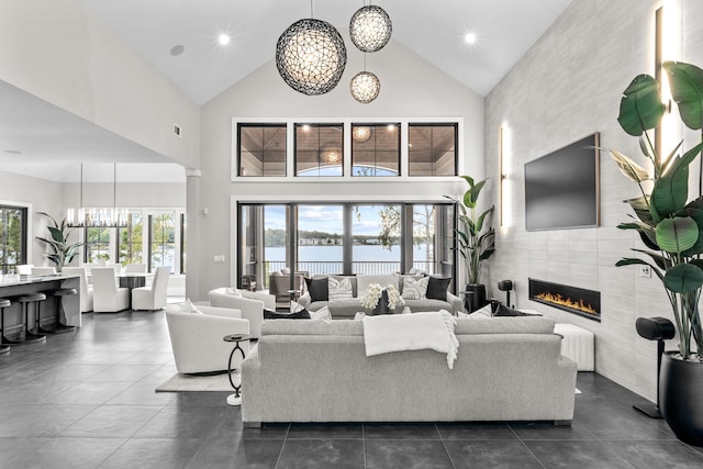 living area featuring high vaulted ceiling, recessed lighting, a notable chandelier, dark tile patterned flooring, and a fireplace