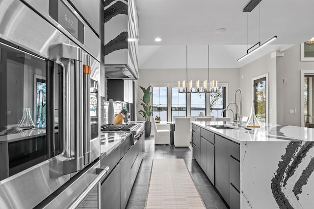 kitchen with hanging light fixtures, a sink, modern cabinets, and a large island with sink