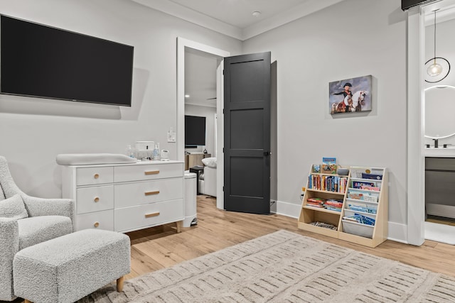 living area featuring light wood-style flooring, baseboards, and crown molding