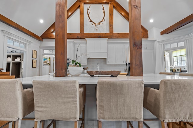 kitchen with white cabinetry, decorative backsplash, and a kitchen breakfast bar