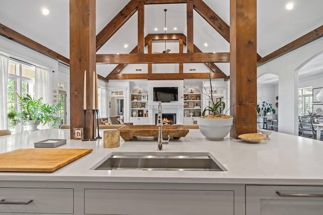 kitchen with high vaulted ceiling, beam ceiling, sink, and a wealth of natural light