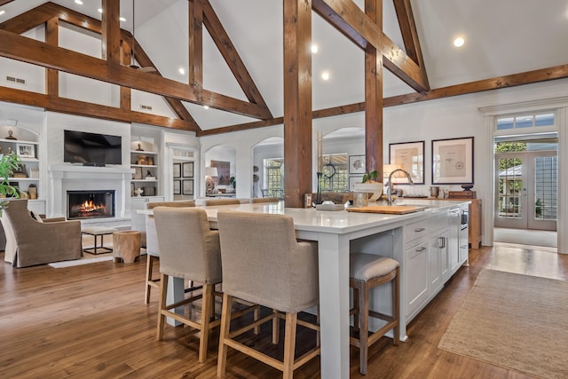 kitchen with a kitchen island, sink, white cabinets, a kitchen bar, and light hardwood / wood-style floors