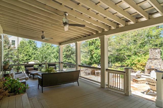 wooden terrace featuring ceiling fan and an outdoor living space with a fireplace