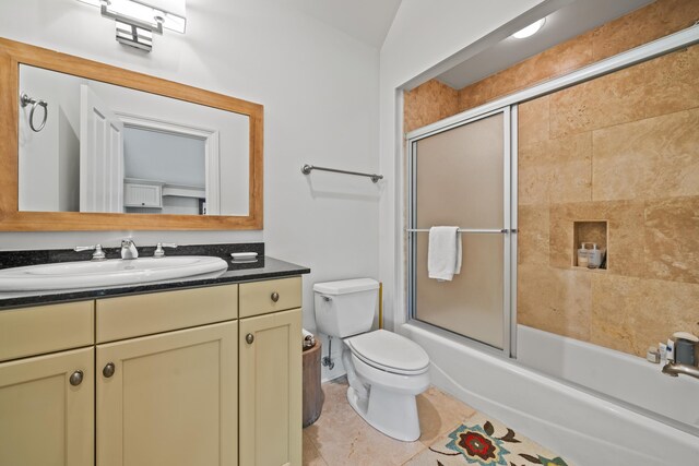 full bathroom with tile patterned flooring, bath / shower combo with glass door, vanity, and toilet