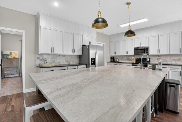 1005 Dennis St, Eatonton, GA 31024 - kitchen featuring appliances with stainless steel finishes, tasteful backsplash, dark wood-type flooring, a kitchen breakfast bar, and recessed lighting