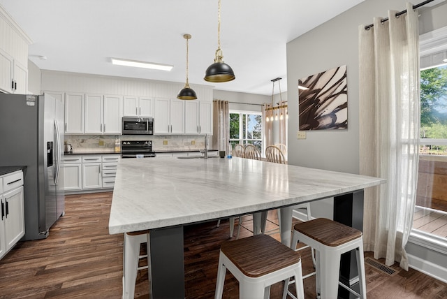 1005 Dennis St, Eatonton, GA 31024 - kitchen with stainless steel appliances, dark wood-style floors, a breakfast bar area, and decorative backsplash