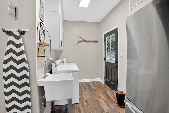 1005 Dennis St, Eatonton, GA 31024 - washroom featuring cabinet space, wood finished floors, and washing machine and dryer